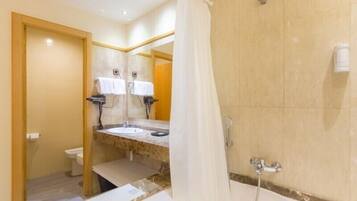 A bathroom with a bathtub, a sink, and a toilet. There are two towel racks with white towels hanging.