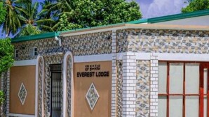 A building labeled "EVEREST LODGE" with a stone facade, a green roof, and a gated entrance. - Everest Lodge  (Hulhudhoo)