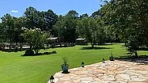 A stone-paved courtyard with a lawn and trees. - Beachwoods Inn (Loris)