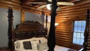 A four-poster bed with a wooden headboard, a white bedspread, and several pillows. - Beachwoods Inn (Loris)