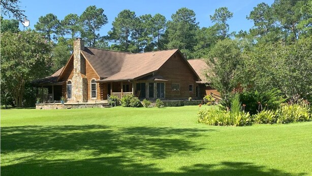 A log cabin with a stone chimney, a porch, and a well-maintained lawn. - Beachwoods Inn (Loris)