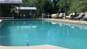 A swimming pool with lounge chairs and a covered area. - Beachwoods Inn (Loris)