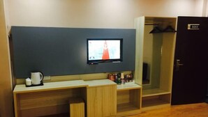 A hotel room with a TV mounted on the wall, a wooden desk with a kettle, and a wardrobe. - 99 Express Hotel (Lixin)