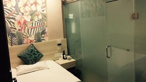 A hotel room with a bed, a nightstand, a telephone, and a glass-enclosed shower area. - 99 Express Hotel (Lixin)