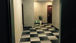 A hallway with a checkered floor, a potted plant, and a door at the end. - 99 Express Hotel (Lixin)