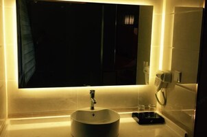 Un baño con un lavamanos redondo, un espejo y un perchero para toallas.