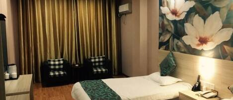 A hotel room with two beds, a desk, a chair, a wall-mounted air conditioner, and a floral mural.
