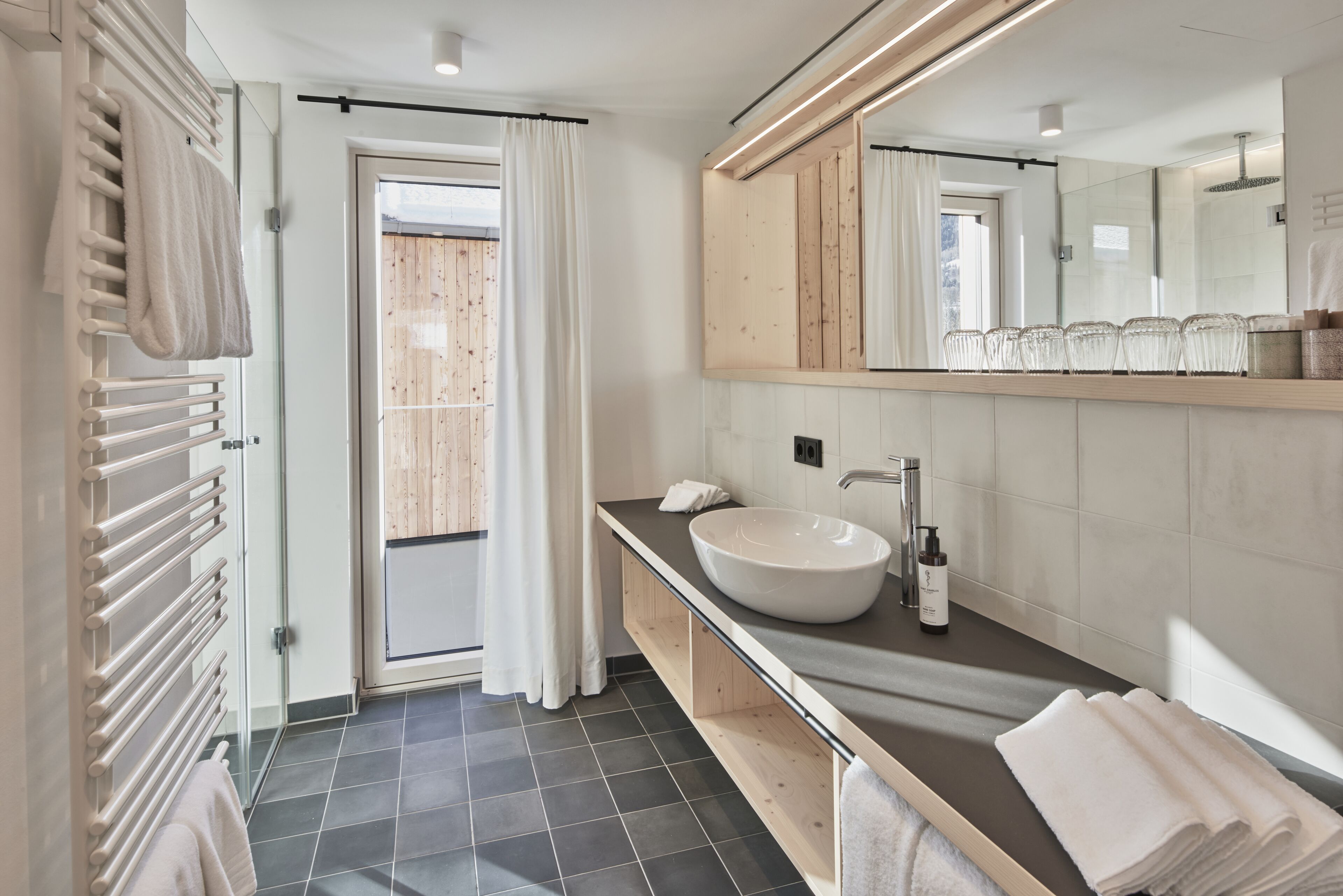 A modern bathroom with a large mirror, a vessel sink, and a towel rack.