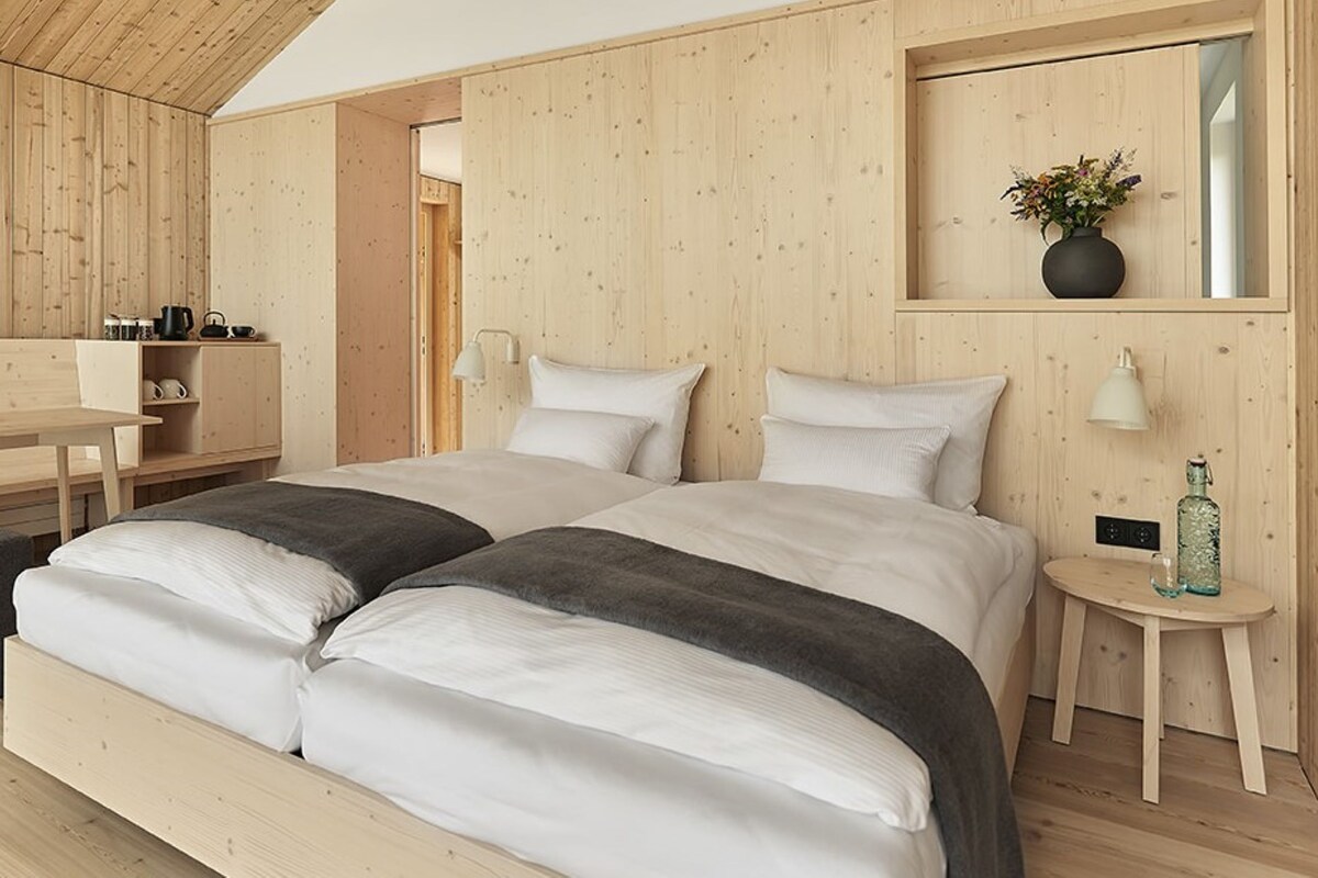 Une chambre à coucher avec un lit en bois, des tables de chevet, un petit bureau et un miroir.