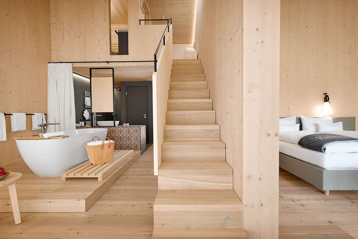 Un intérieur moderne avec une baignoire, un escalier en bois et un lit.