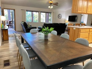 Enjoy meals in this inviting dining area with a large table and comfortable seating for six, surrounded by a view of the trees.