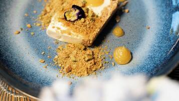 A dessert on a blue plate with crumbled topping and two dollops of yellow sauce.