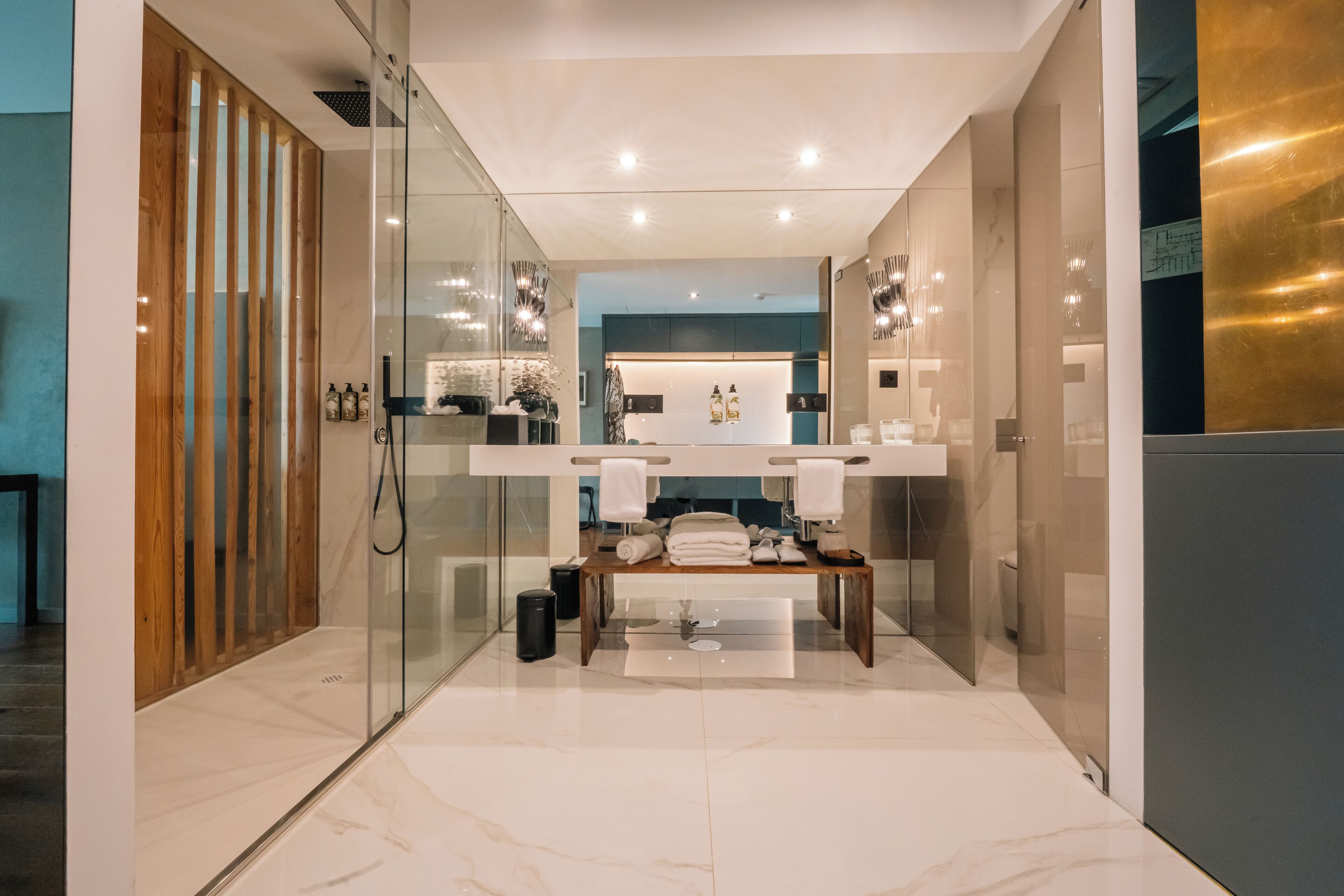 A modern bathroom with a glass shower enclosure, a wooden vanity, and a marble floor.