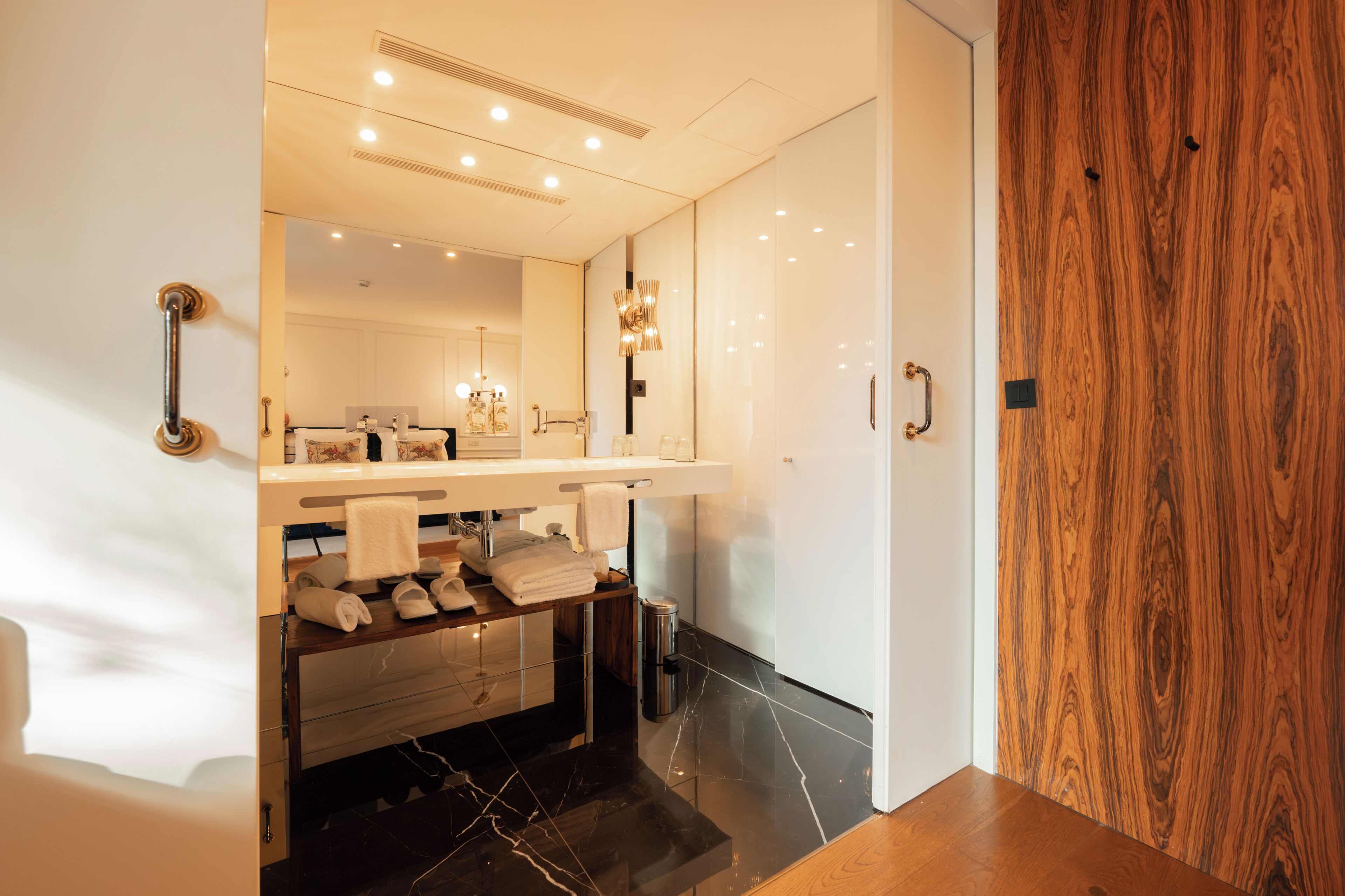 Un baño moderno con tocador, espejo, perchero y una puerta de madera.