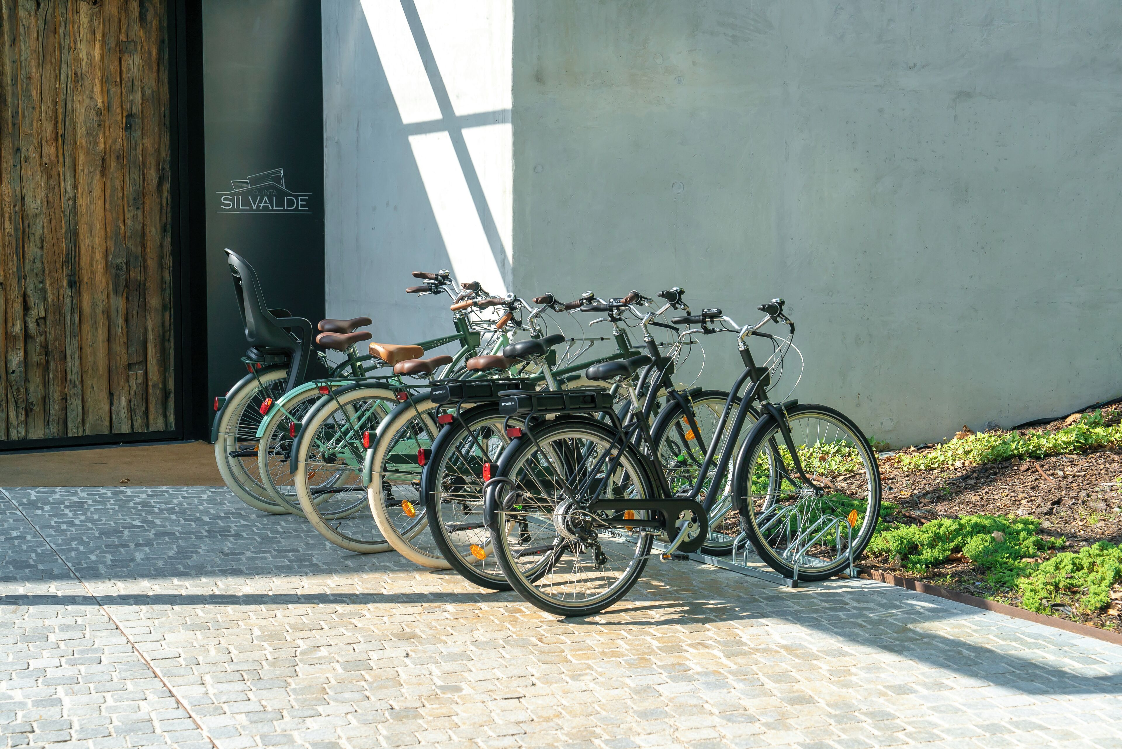 A row of bicycles parked outside a building with a wooden door and a sign that reads "SILVALDE".