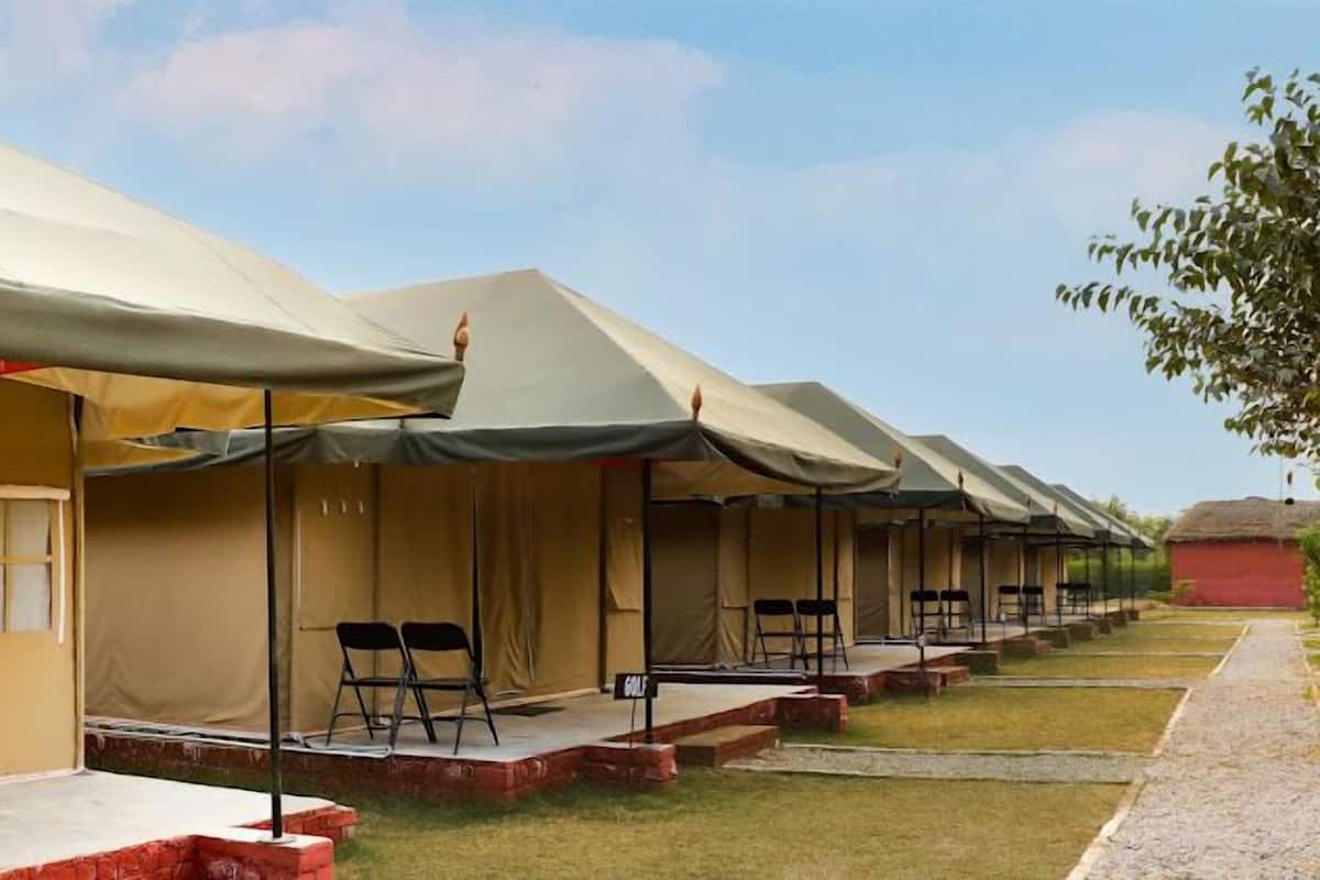 A row of tents with a small stage and chairs in front, suggesting a temporary event or accommodation setup.