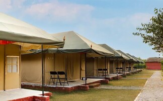 A row of tents with a small stage and chairs in front, suggesting a temporary event or accommodation setup.