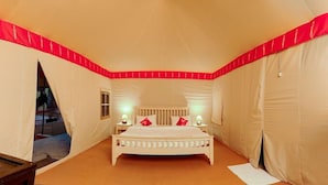 Una habitación tipo tienda de campaña con una cama, dos lámparas de noche y una ventana.
