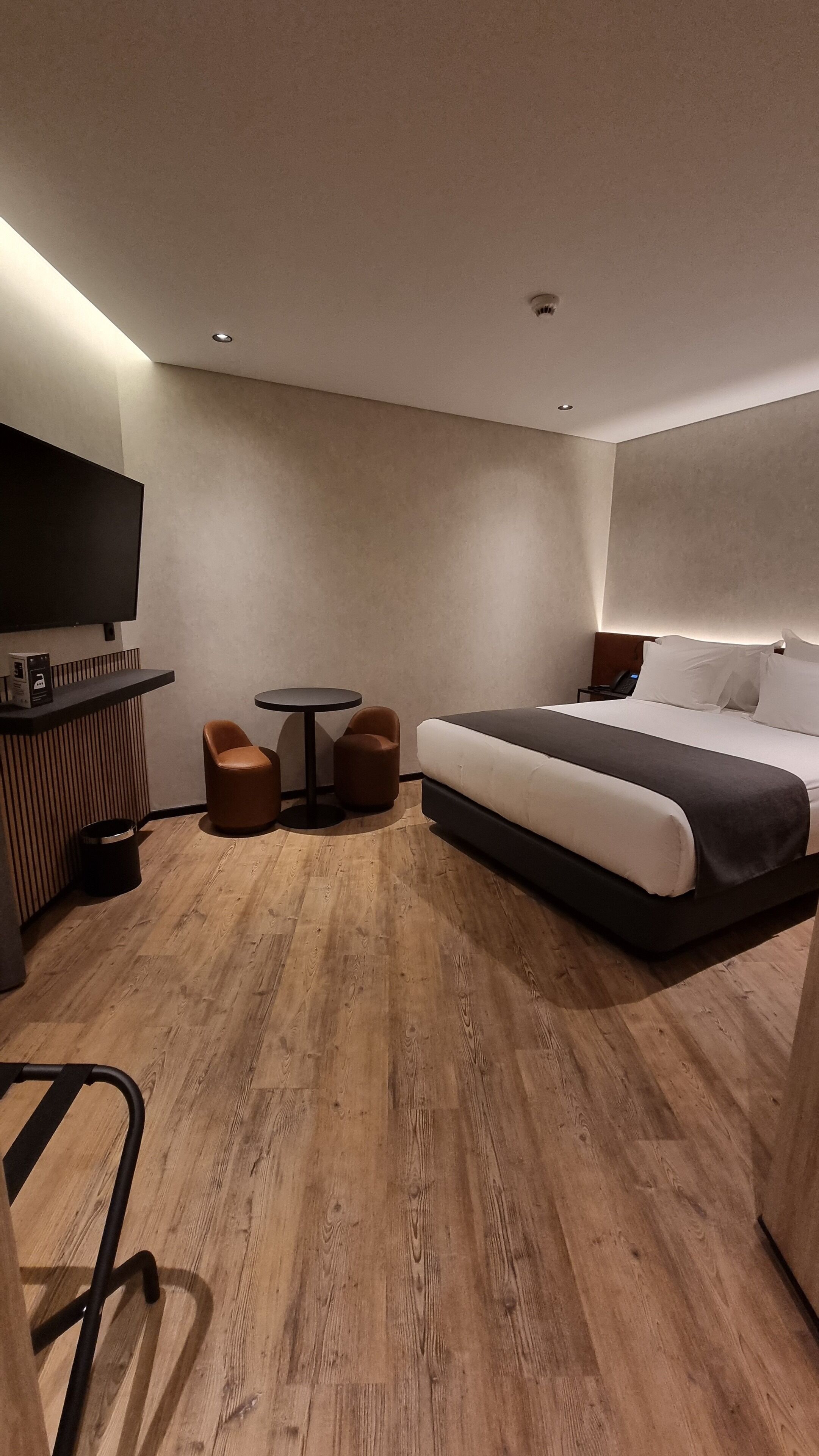 Habitació d'hotel moderna amb un llit gran, una taula de treball, una cadira i una televisió.