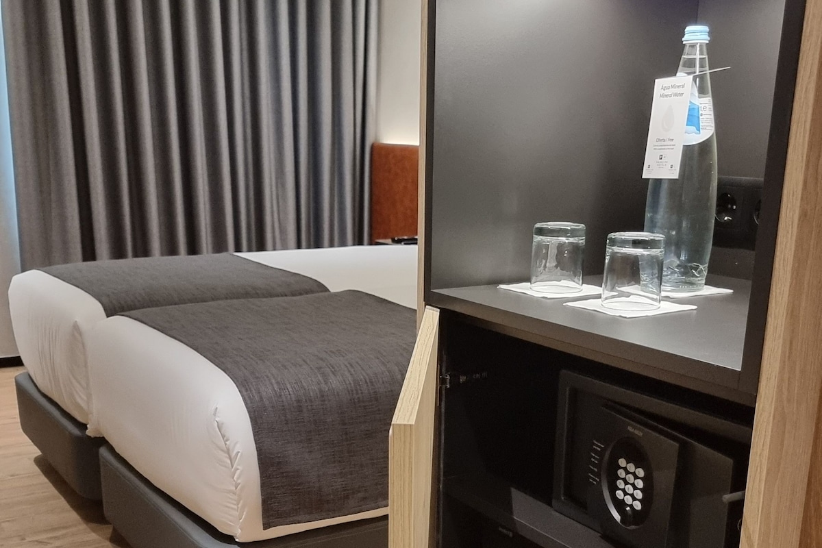 Ein modernes Hotelzimmer mit Bett, Minibar und Spiegel.