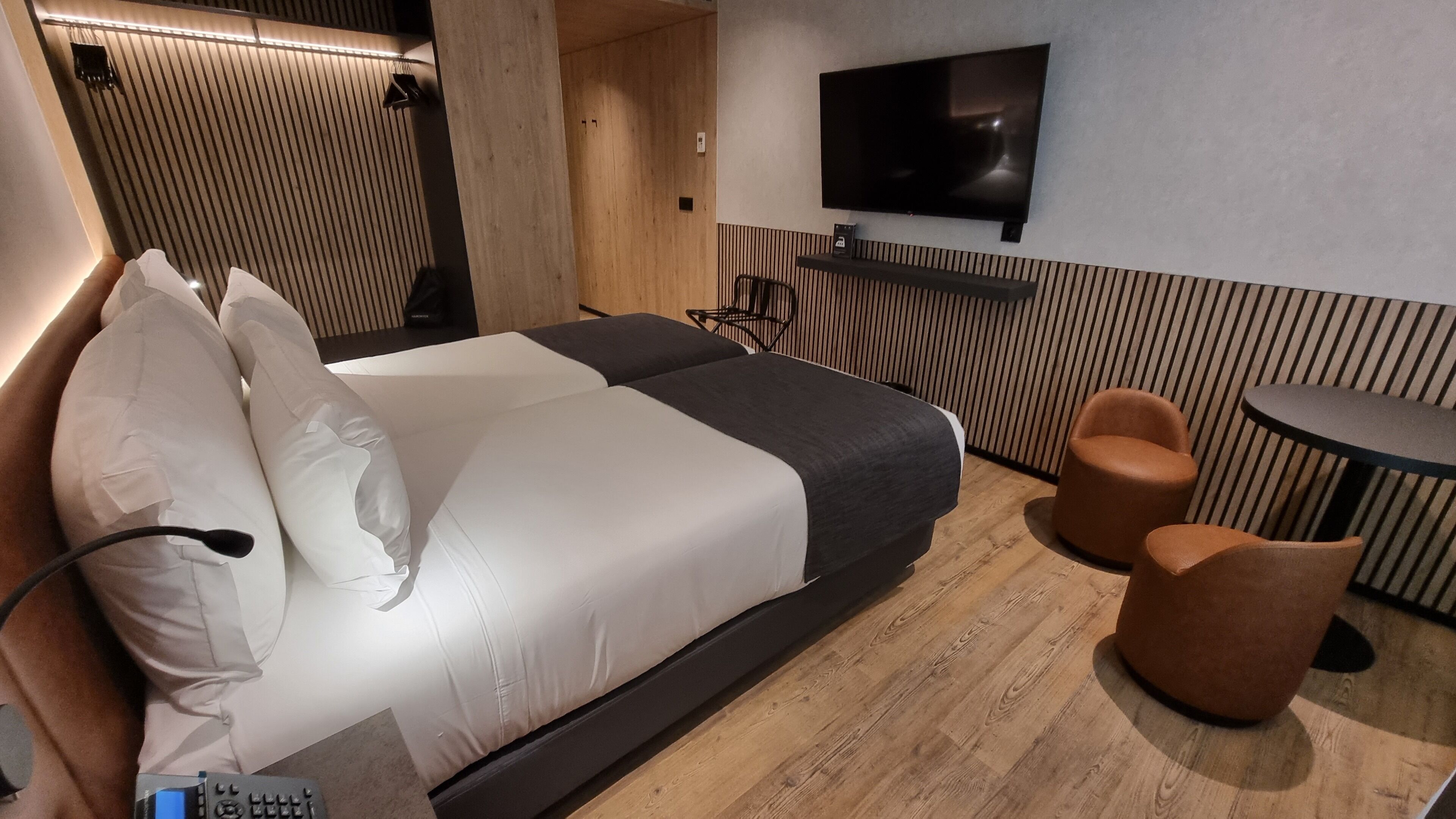 Una habitación de hotel moderna con una cama grande, un televisor de pantalla plana y dos sillones.