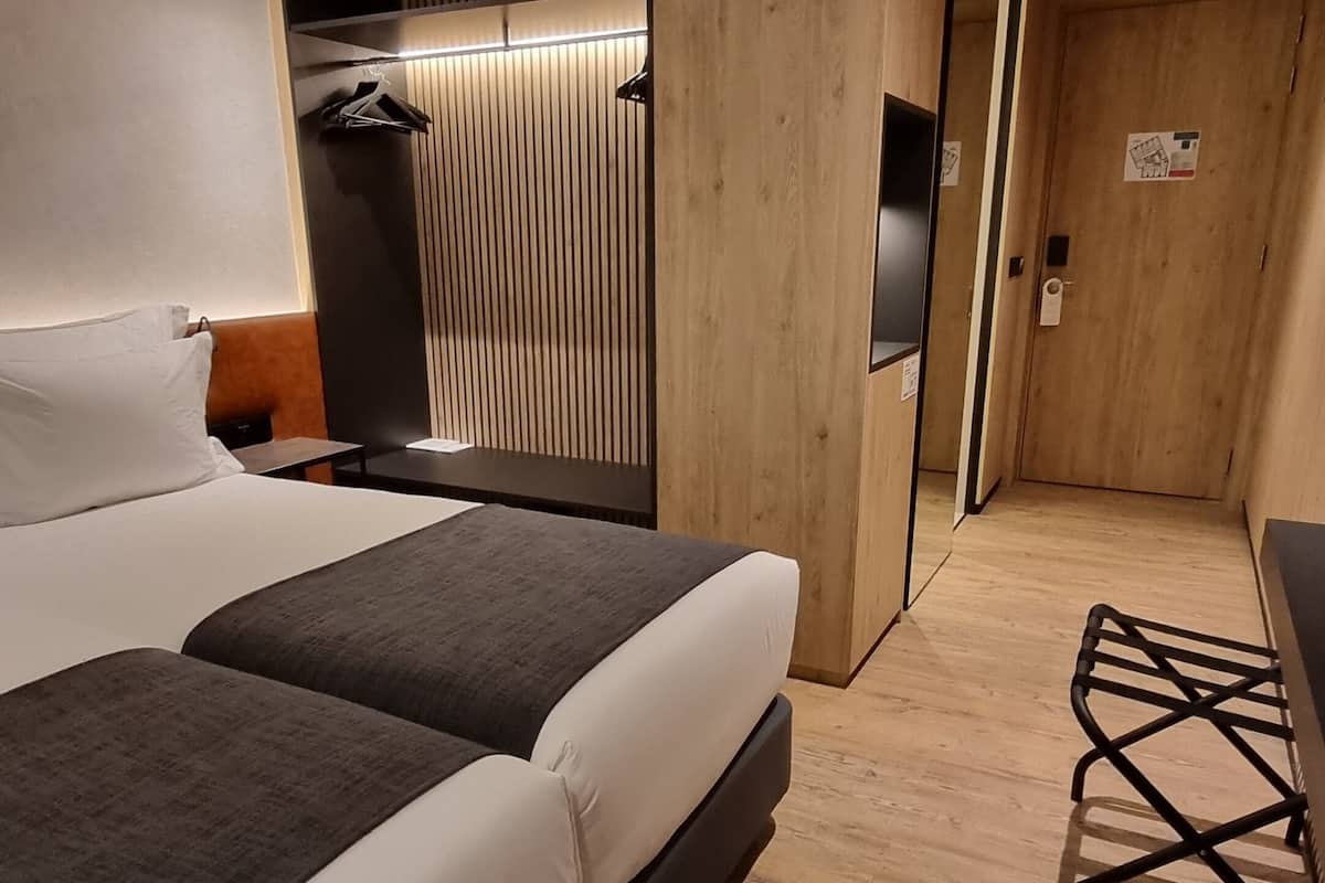 Une chambre d’hôtel moderne avec un grand lit, une armoire en bois, un bureau et une chaise.