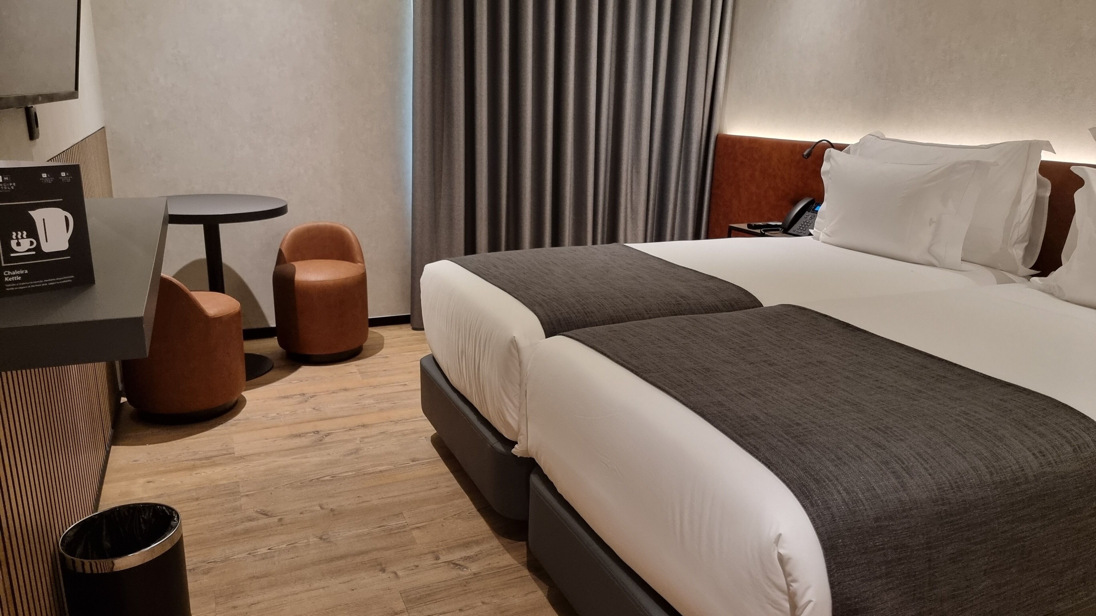 Una habitación de hotel con una cama, un escritorio, una silla y un cesto de basura.