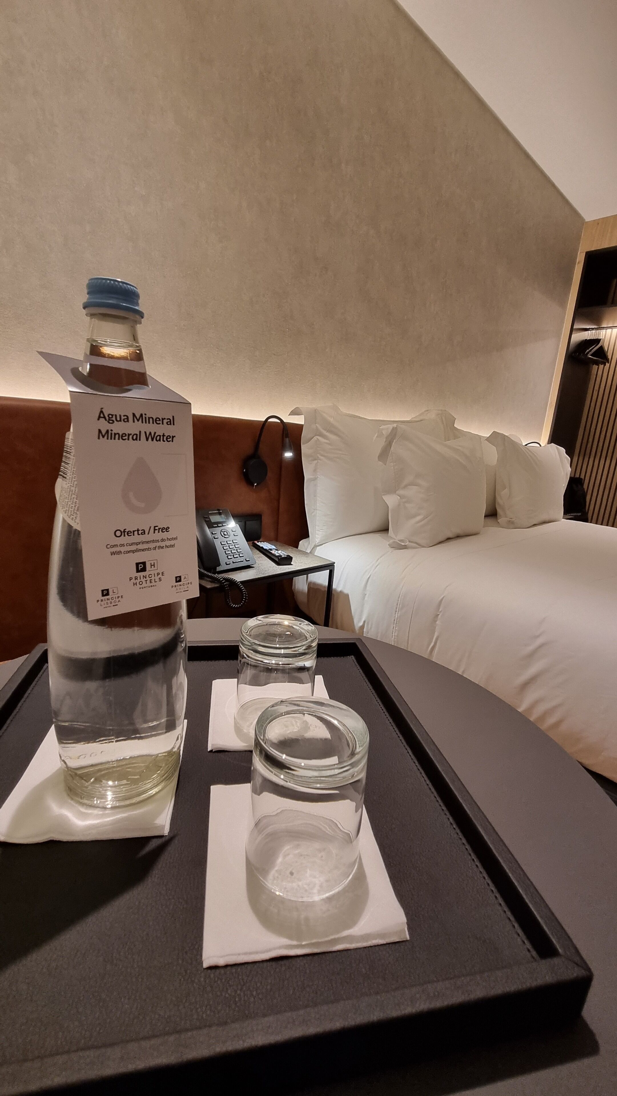 A hotel room with a minibar containing mineral water and a bottle labeled 'Água Mineral Mineral Water.'