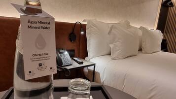 A hotel room with a minibar containing mineral water and a bottle labeled 'Água Mineral Mineral Water.'