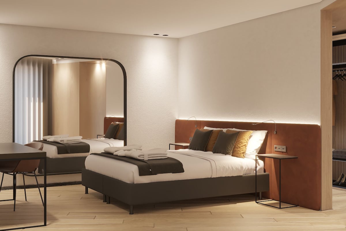 Une chambre d’hôtel moderne avec un grand lit, un bureau et un miroir.