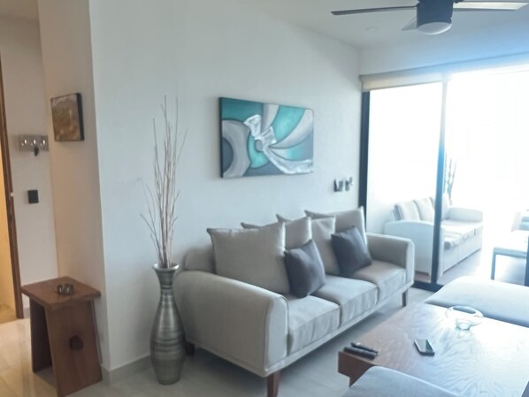 A modern living room with a sofa, a vase, and a painting on the wall. - Beautiful 3 Bed 2 Bath Condo 1/2 a block to the beach. 5 min to Bucerias Centro (Bucerías)