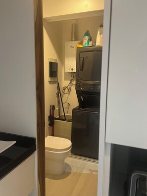 Une petite cuisine équipée d’un lave-linge, de toilettes et d’un évier.