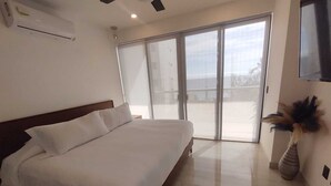 Ein Hotelzimmer mit einem großen Bett, einem flachbildfernseher an der Wand und einer Glastür, die auf einen Balkon führt.