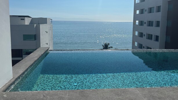 Ein Pool mit Blick auf das Meer, umgeben von modernen Gebäuden.