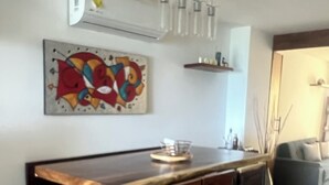 Ein moderner Essbereich mit einem Holztisch, schwarzen Metallbeinen und einem farbenfrohen abstrakten Gemälde an der Wand.