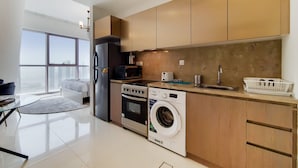 A modern kitchen with stainless steel appliances, wooden cabinets, and a large window offering a city view.