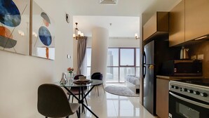 A modern kitchen with a refrigerator, oven, and dining area with chairs and a table.
