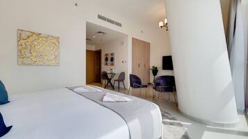 A hotel room with a large bed, a seating area with chairs, and a dining table.