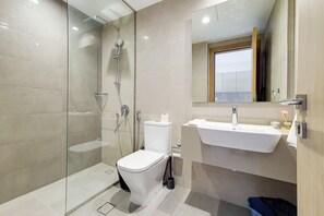 A modern bathroom with a glass-enclosed shower, a white toilet, and a sink with a mirror above it.