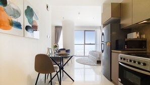 A modern kitchen with a dining area, stainless steel appliances, and a large window offering a view. - GreenFuture - Luxe Studio In Trade Center With Downtown Views (Dubai)