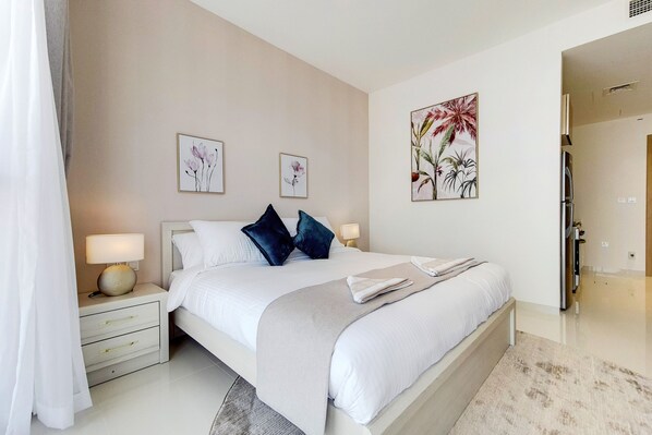 Un dormitorio moderno con una cama grande, mesitas de noche con lámparas y decoración floral en la pared.
