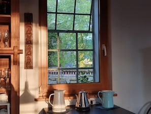 Eine Küche mit Fenster, einer Kaffeemaschine und einer Tasse auf der Arbeitsfläche.