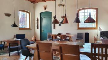 A dining area with a wooden table and chairs, a green door, and pendant lights.
