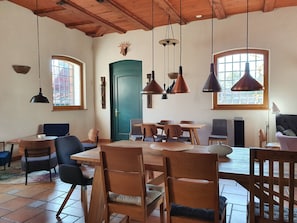 Comedor con mesa y sillas de madera, una puerta verde y lámparas colgantes.