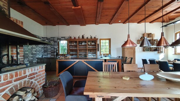 A rustic kitchen with a brick wall, wooden ceiling, and a bar area with shelves of bottles and glasses. - Single room-#9 LütunLüt NEU im EG-Standard-Ensuite with Bath (Groß Dratow)