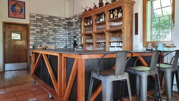 A bar area with a brick wall backsplash, wooden shelves with glasses, and a door with a window.