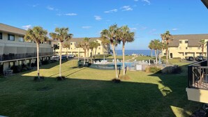 Cortile d'hotel con piscina, palme e vista sull'oceano.