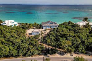 A coastal property with a large house surrounded by dense tropical vegetation and a beach. - Sea Loft: Unparalleled Oceanfront Serenity in a Newly Rebuilt Paradise (Elbow Cay)