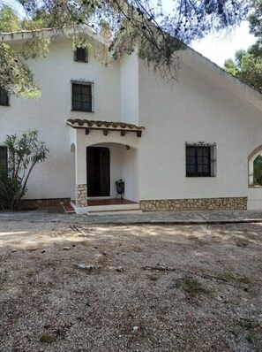 A two-story house with a white exterior, a stone base, and a tiled roof.