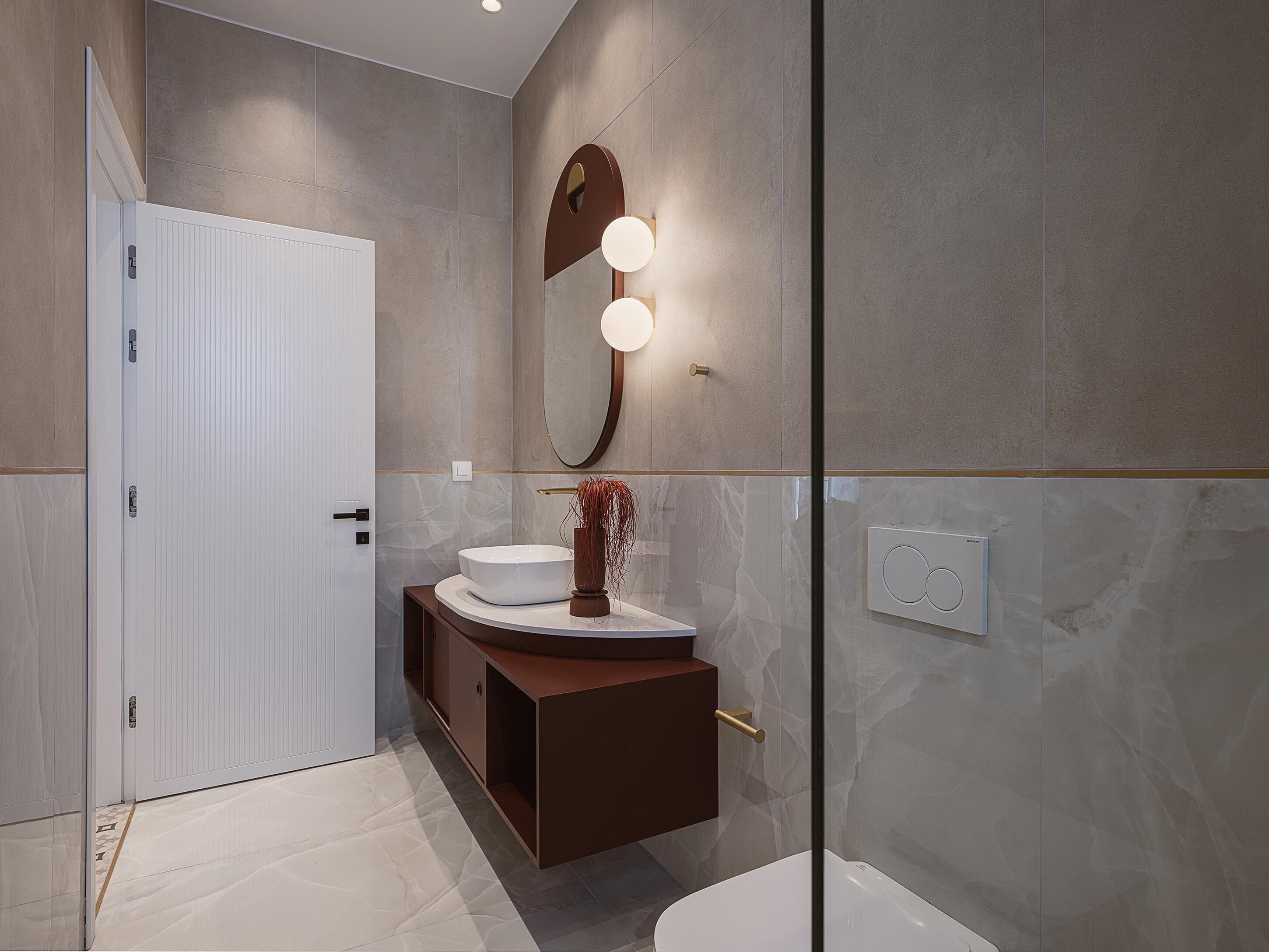 Un baño moderno con inodoro blanco, tocador con un espejo grande e iluminación, y zona de ducha.